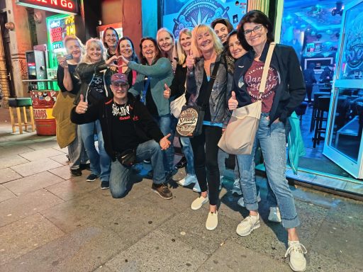 Viel Spaß bei der Kieztour Gruppe von zwölf Personen, die fröhlich vor einem bunten, leuchtenden Hintergrund posieren.